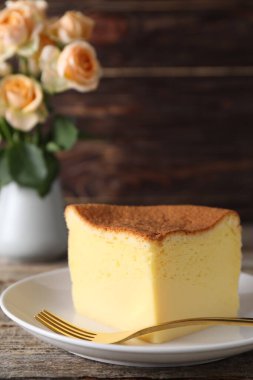 Piece of tasty Japanese Castella sponge cake and fork on wooden table, closeup
