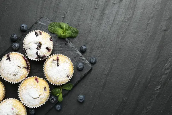 Yaban mersinli lezzetli çörekler, pudra şekeri ve siyah desenli masada nane şekeri, düz yatak. Metin için boşluk