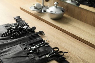 Berber dükkanında, açık ahşap masanın üzerinde birçok farklı berber aleti var.