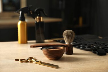 Berber dükkanında, açık ahşap masanın üzerinde birçok farklı berber aleti var.