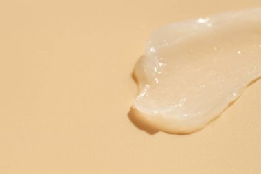 Bej arka planda nemlendirici dudak kremi, yakın plan. Metin için boşluk