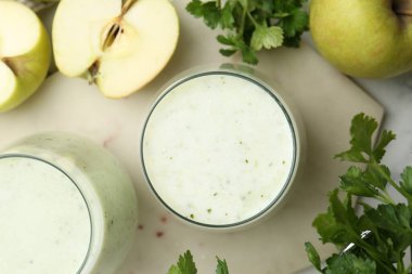 Sağlıklı maydanoz bardaklarda, yapraklarda ve elmalarda masada, düz bir şekilde yatıyor.