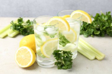 Açık gri masada maydanozlu, limonlu ve kerevizli sağlıklı içecek.