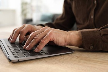 İçerideki masada dizüstü bilgisayar kullanan kıdemli bir adam, yakın plan.