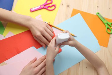 Anne ve kızı ahşap masada el yapımı bir proje yapıyor.