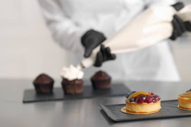 Şekerlemecinin masada kremayla kapkek süslemesi, seçici odaklanma