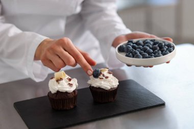 Şekerci, masayı yaban mersinli kek ile dekore ediyor.