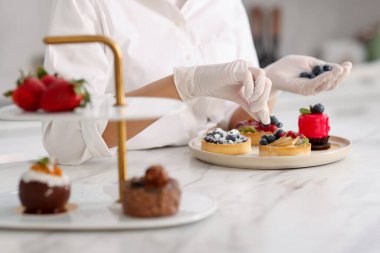 Şekerci tartı yaban mersiniyle süslüyor, yakın plan.