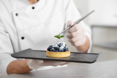 Şekerci, mutfaktaki gri masada nane şekerli tart hazırlıyor, yakın plan.