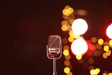 Koyu kırmızı arka planda bulanık ışıkları olan klasik mikrofon. Müzik ekipmanları
