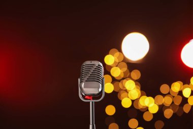 Koyu kırmızı arka planda bulanık ışıkları olan klasik mikrofon. Müzik ekipmanları