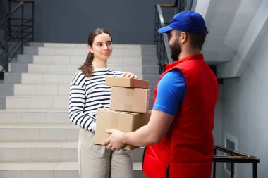 Kurye içerideki merdivenlerdeki alıcıya paket veriyor.