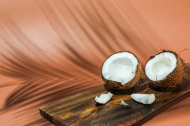 Açık kahverengi arka planda tropikal palmiyelerin taze hindistan cevizi ve gölgesi, yakın plan. Metin için boşluk