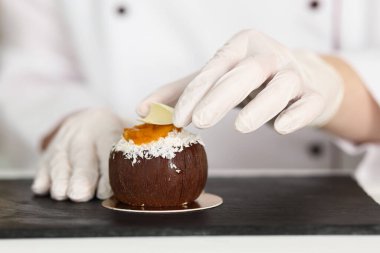 Mutfaktaki beyaz ahşap masada lezzetli bir tatlıyı dekore eden şekerci, yakın plan.