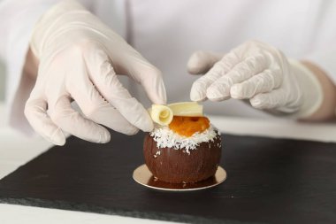 Mutfaktaki beyaz ahşap masada lezzetli bir tatlıyı dekore eden şekerci, yakın plan.