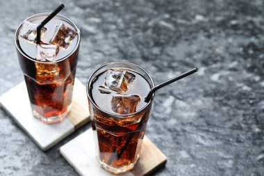 Kolayı buz küpleriyle tazelemek ve koyu dokulu masada pipetler, yakın plan. Metin için boşluk