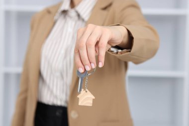 Emlakçının elinde ev şeklindeki anahtarlık var.