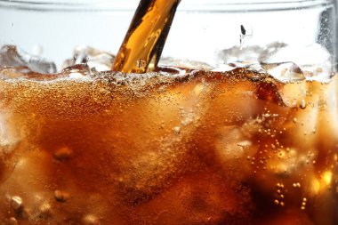 Hafif arkaplan ve makro görüntüye karşı ferahlatıcı kola bardağa dökülüyor