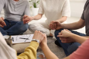 Grup psikoterapi seansı sırasında el ele tutuşan insanlar kapalı mekanda, yakın çekim