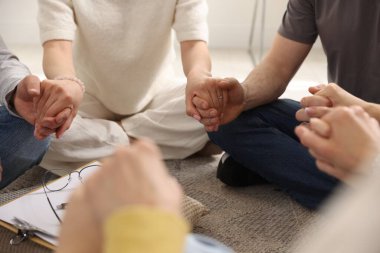 Grup psikoterapi seansı sırasında el ele tutuşan insanlar kapalı mekanda, yakın çekim