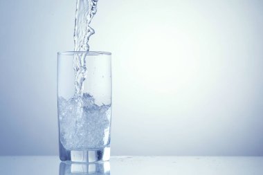 Açık mavi arka planda ferahlatıcı soda bardağına dökülüyor, yakın plan. Metin için boşluk