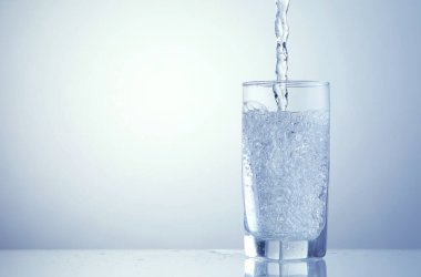 Açık mavi arka planda ferahlatıcı soda bardağına dökülüyor, yakın plan. Metin için boşluk