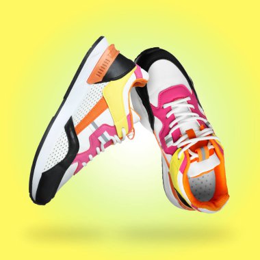 Sarı arkaplanda havadaki şık parlak spor ayakkabılar