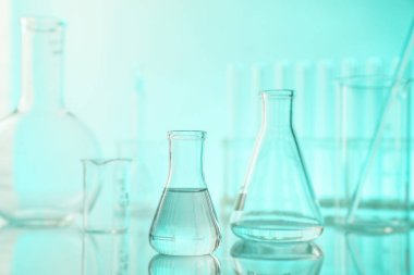 Aynanın yüzeyinde turkuaz arka plana karşı laboratuvar camı var.