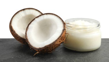 Cam kavanozda organik hindistan cevizi pişirme yağı ve beyaz arka planda siyah masada yarım meyve.