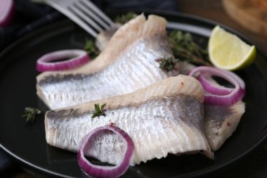 Salamura ringa fileto soğan halkaları, kekik ve limon, yakın plan.