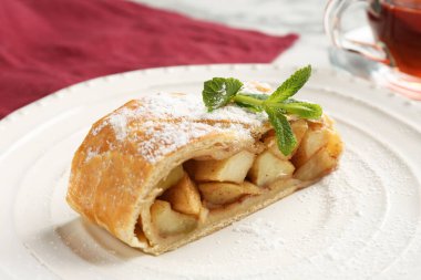 Bir parça lezzetli elmalı turta, üzerine pudra şekeri ve nane şekeri, yakın plan.