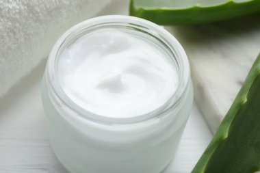 Beyaz ahşap arka planda krema ve aloe yaprakları, yakın plan