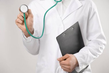 Steteskop ve arkaplanda pano olan doktor, yakın plan.