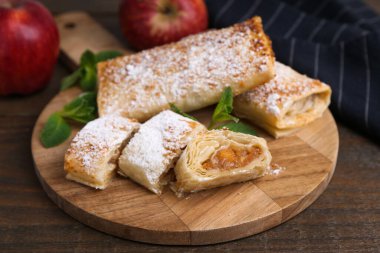 Ahşap masada pudra şekeri, nane ve meyveli elmalı turtalar, yakın plan.