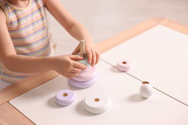 Motor beceri geliştirme. Oyuncak piramitlerle oynayan küçük kız kapalı bir masada, yakın plan.