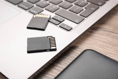 Sabit disk, SD hafıza kartları ve dizüstü bilgisayarlar ahşap masada, yakın plan.