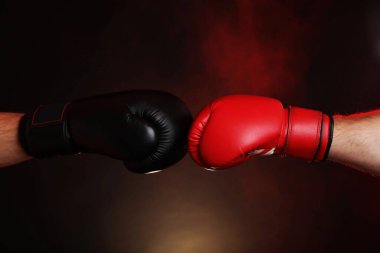 Boks eldivenli adamlar karanlık arka planda dumanla savaşıyor.