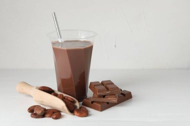 Lezzetli çikolatalı süt, barlar ve beyaz ahşap masada kakao çekirdekleri. Metin için boşluk