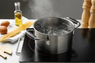 Kaynar suyla pişirme tenceresi ve beyaz masa üzerinde gri arka plan, yakın çekim