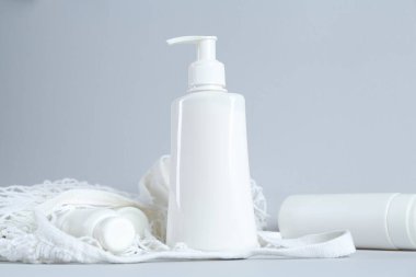 Açık gri arka planda birçok kozmetik ürünü ve ağ torbası