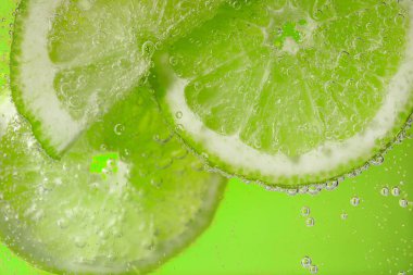 Açık yeşil arka planda limon dilimli soda, yakın plan.