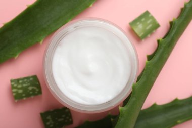 Kavanozda aloe vera özütüyle nemlendirici krem ve pembe arka planda yapraklar.