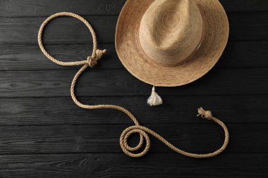 Pamuk ipten yapılmış kement ve siyah ahşap arka planda hasır şapka, düz yatıyordu.