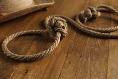 Pamuk ipten ve ahşap arka planda hasır şapkadan yapılmış kement, yakın plan.