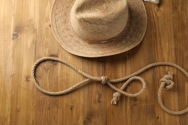 Pamuk ipten yapılmış kement ve ahşap arka planda hasır şapka, düz yatıyordu.