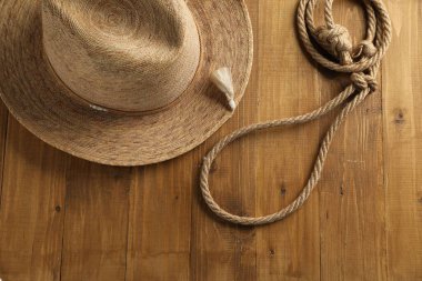 Pamuk ipten yapılmış kement ve ahşap arka planda hasır şapka, düz yatıyordu.