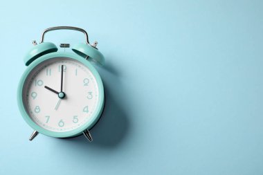 Açık mavi arka planda turkuaz alarm saati, üst manzara. Metin için boşluk