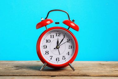 Ahşap masada açık mavi zemin üzerinde bir kırmızı alarm saati