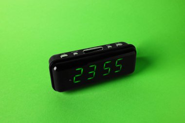 Saat 23: 55 'i gösteren dijital alarm saati yeşil arka planda.