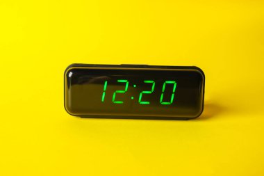 Sarı arkaplanda saat 12: 20 'yi gösteren dijital alarm saati